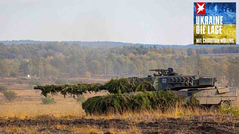 A Leopard 2 tank drives through the terrain camouflaged with fir green