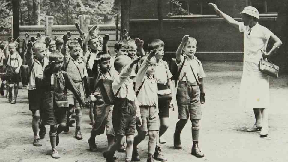 A primary school teacher greets her students in Berlin in 1935 with the Hitler salute