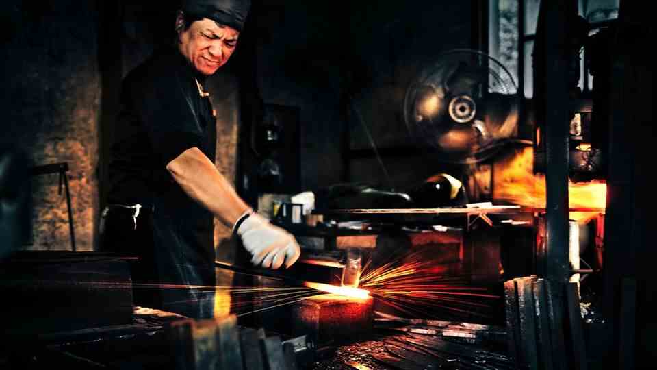 With full force: The Japanese blacksmith Shigeki Tanaka lets his hammer whiz down red-hot crude steel, sparks fly in all directions