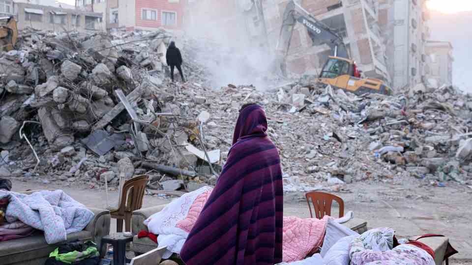A woman stands in front of the rubble of her home in the Turkish city of Hatay