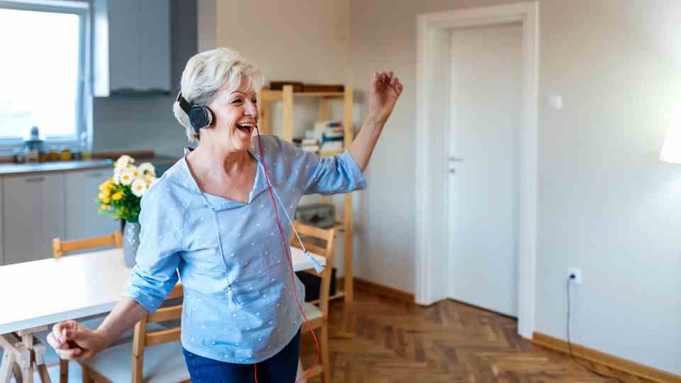 Woman with headphones dancing in the kitchen