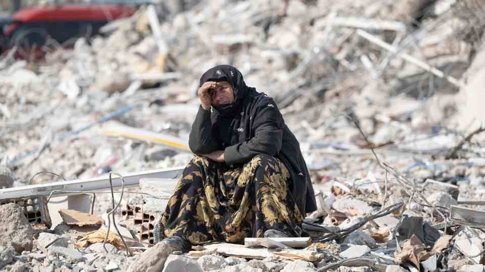 A woman sits among rubble after the quake in Turkey and Syria in the city of Antakya.