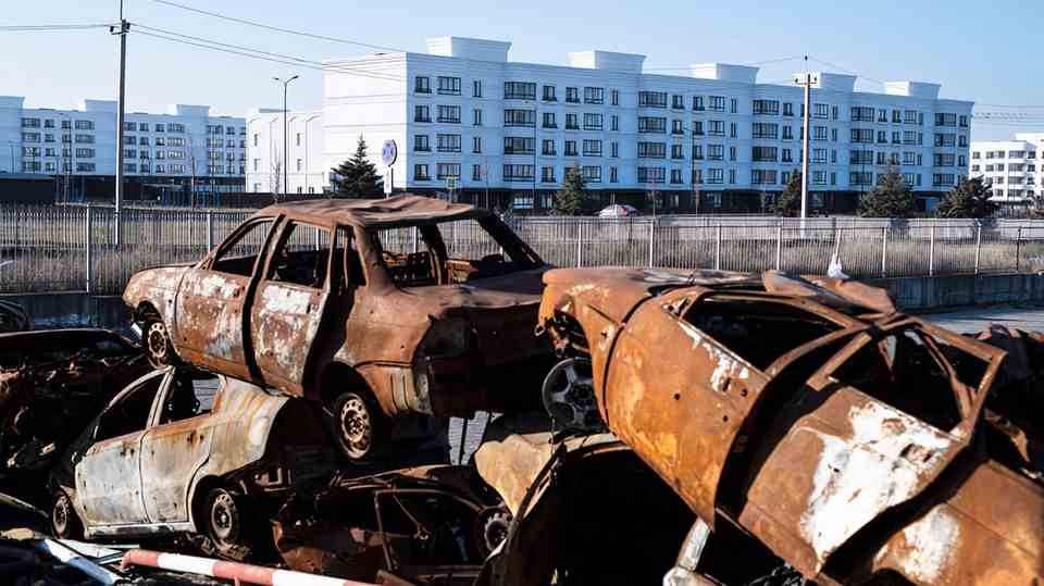 Vor einer Neubausiedlung in Mariupol türmen sich ausgebrannte Autos