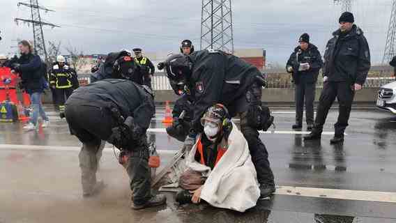 Police officers cut free a climate activist glued to a bridge.  © dpa-Bildfunk Photo: Steven Hutchings