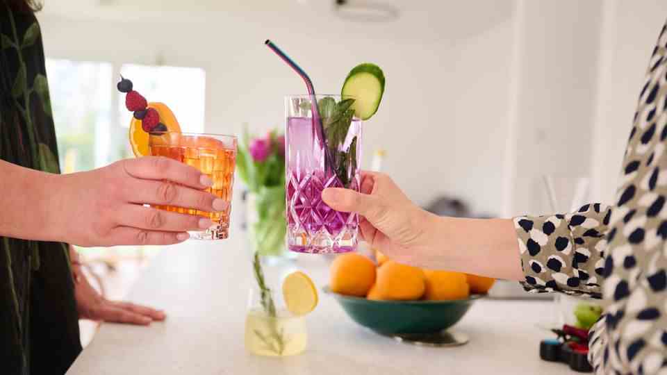 Two women toast with non-alcoholic cocktails (Aperol Spritz and Gin Tonic).