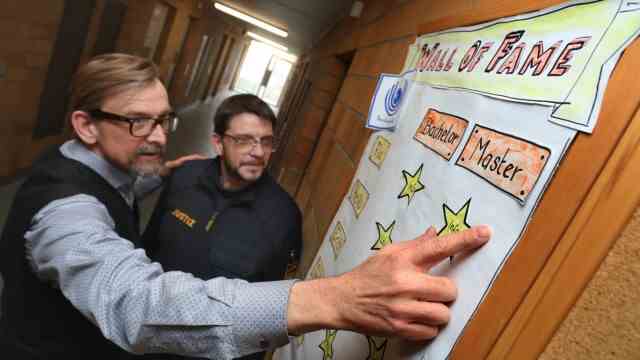 Würzburg: Pedagogue Arnd Bartel (left) and Reinhard Sachse from the prison's educational service support the student offenders.  The graduates of the various courses are honored with stars on a poster.