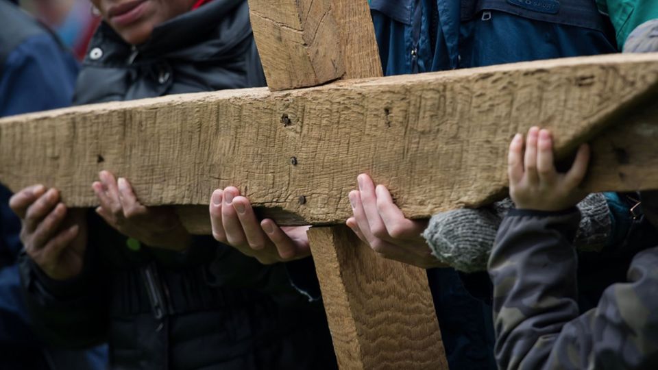 Believers hold a large cross during the ecumenical Stations of the Cross procession on Good Friday in Lübeck.