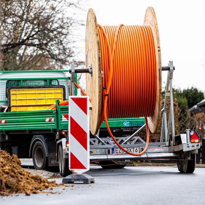 A cable drum with fiber optic cable stands on a construction site between barriers on the trailer of a truck.  |  dpa