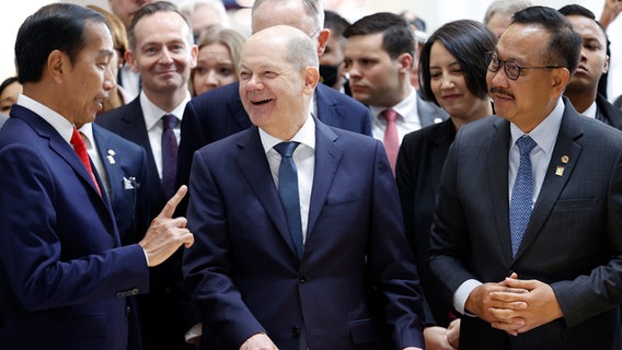 Chancellor Olaf Scholz (SPD, M) laughs next to Joko Widodo (l), President of Indonesia, at a booth in front of a model during the opening tour of the Hannover Messe industrial fair.  © dpa-Bildfunk Photo: Michael Matthey