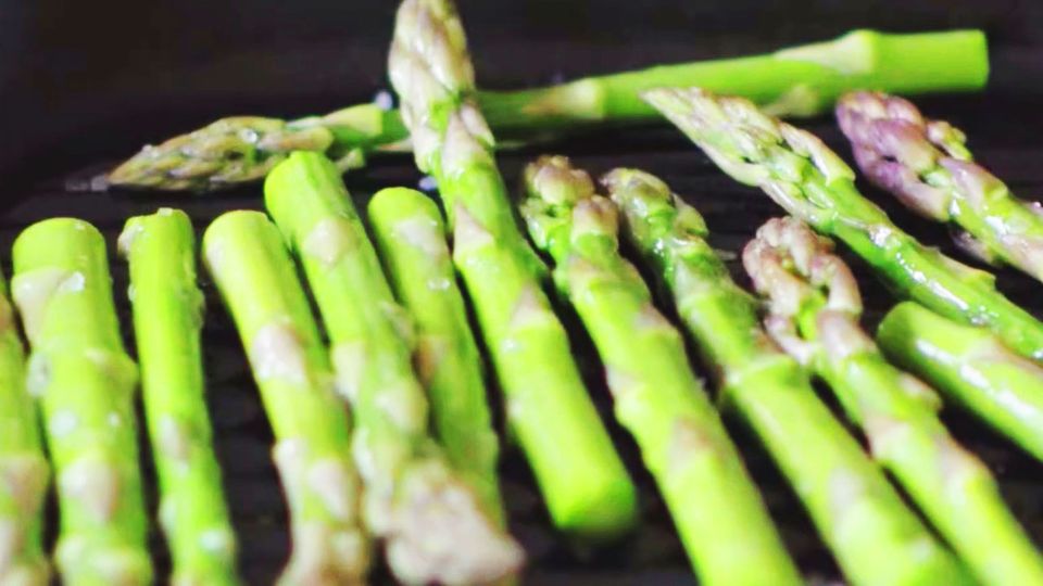 Several spears of asparagus are fried in a pan