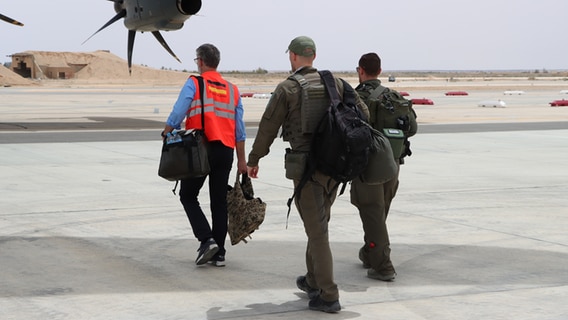 Three men walk to a Bundeswehr transport aircraft at the air force base in Al-Asrak.  © Bundeswehr Photo: Hultgren