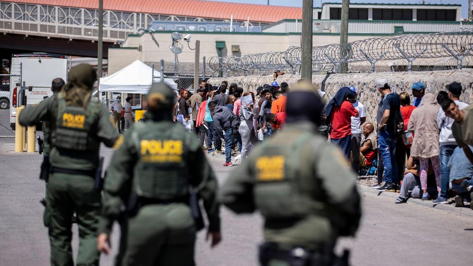 Beamte der U.S. Customs and Border Protection beobachten eine Gruppe von Migranten, die an der Grenze bei El Paso auf die Einwanderung in die USA warten