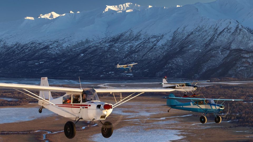 Four machines fly in formation along the Knik River