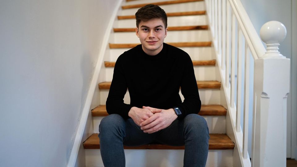 Student Liam Kastner sits on a staircase in a black top