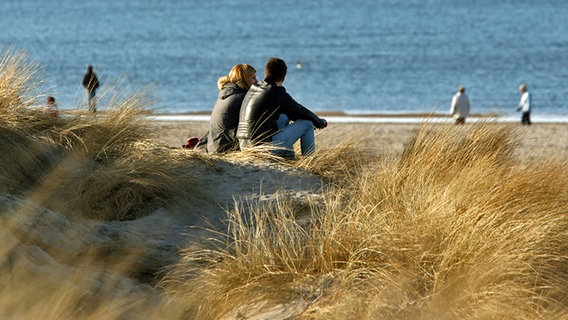 Two people sit in the sun on the Baltic Sea beach.  © dpa photo: Bernd Wüstneck