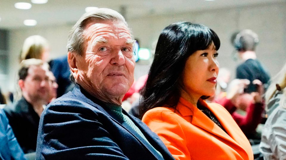 Gerhard Schröder and his wife Soyeon Schröder-Kim sit in the audience