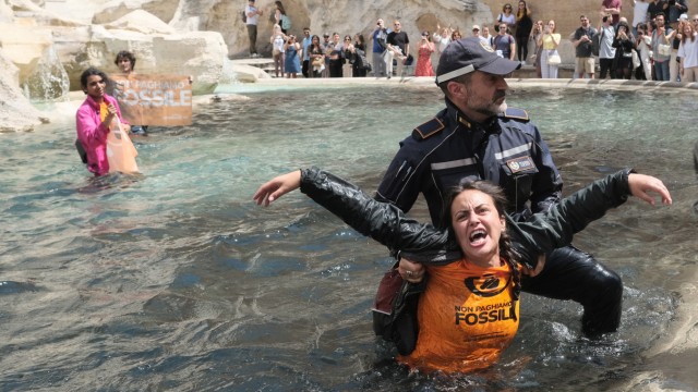 Rome: A policeman leads an activist from the Trevi Fountain.