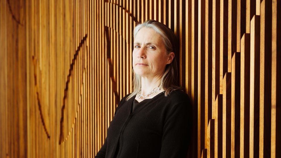 Fiona Hill is leaning against a wooden wall