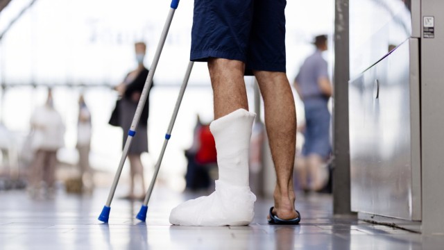 Insurance: A traveler with a leg in a cast and crutches: After an accident, the agreed sum is often paid out in one fell swoop.