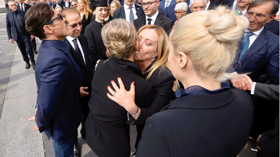 Prime Minister Giorgia Meloni hugs members of the Berlusconi family.  A woman hugs another.