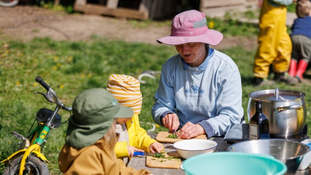Raising children: The head of the farm kindergarten in Giebelstadt, Elke Kleid, prepares the soup for lunch outdoors with two children.