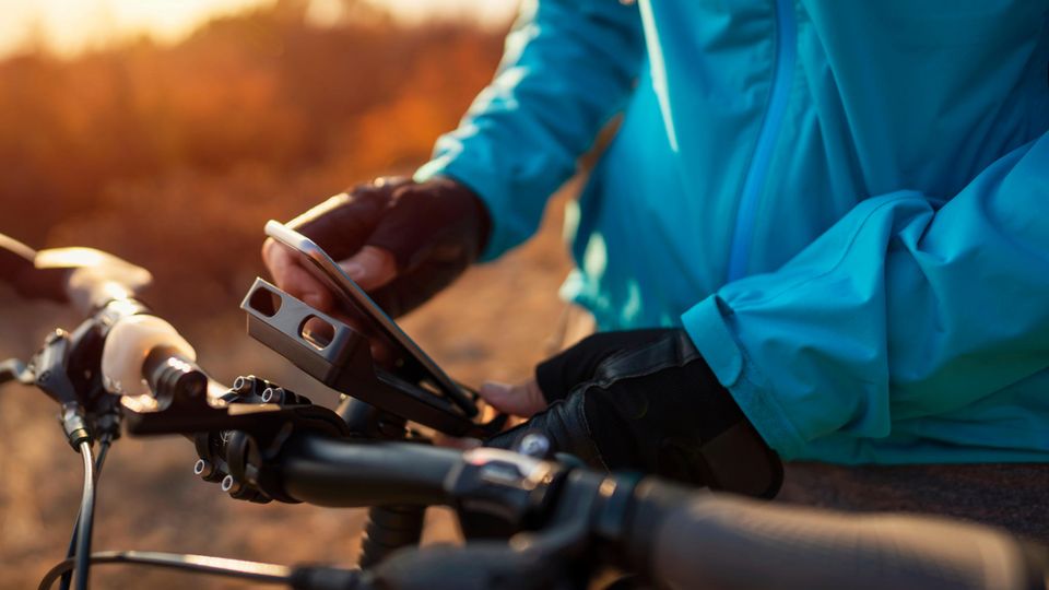 A man clamps his smartphone into the cell phone holder with power bank on the bike