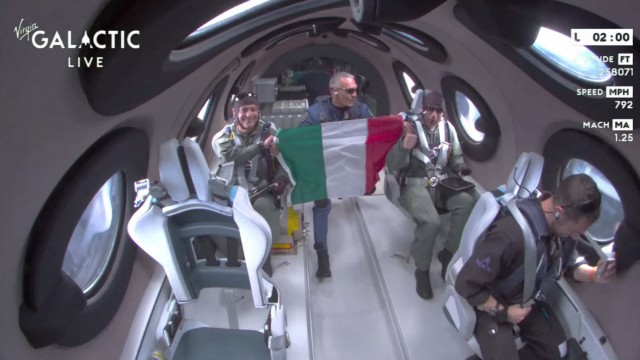 Spaceflight: A screenshot of a video showing the interior of the spacecraft during its sojourn in space.  The Italian crew members can be seen waving an Italy flag.