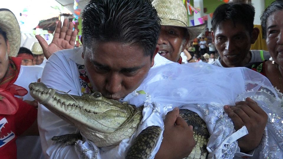 San Pedro Huamelula Mayor Victor Hugo Sosa kisses a female caiman.