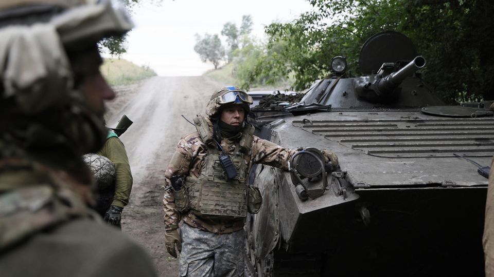 Ukrainian soldiers next to an armored personnel carrier.