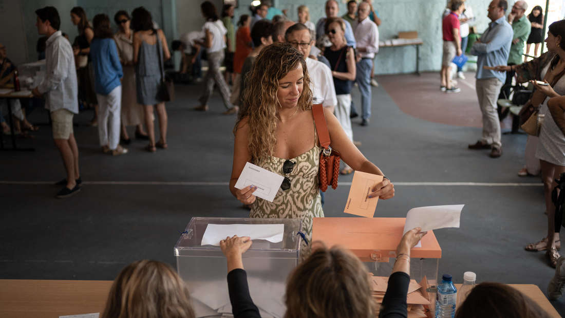 A voter casts her ballot in a ballot box in a Spanish school