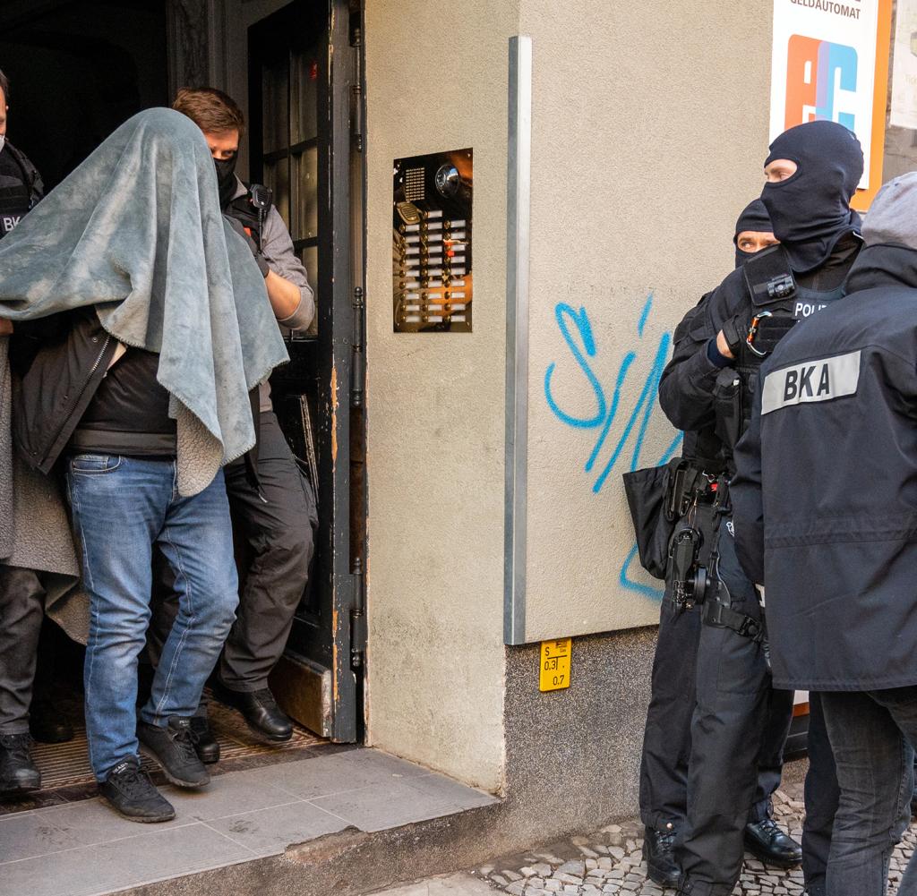 A man is taken away by police with a blanket over his head during a raid.  Overall, the police assigned 582 people to clan crime