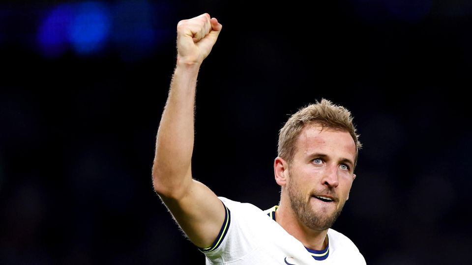 Harry Kane, still in the Tottenham Hotspur jersey, raises his right fist into the night sky