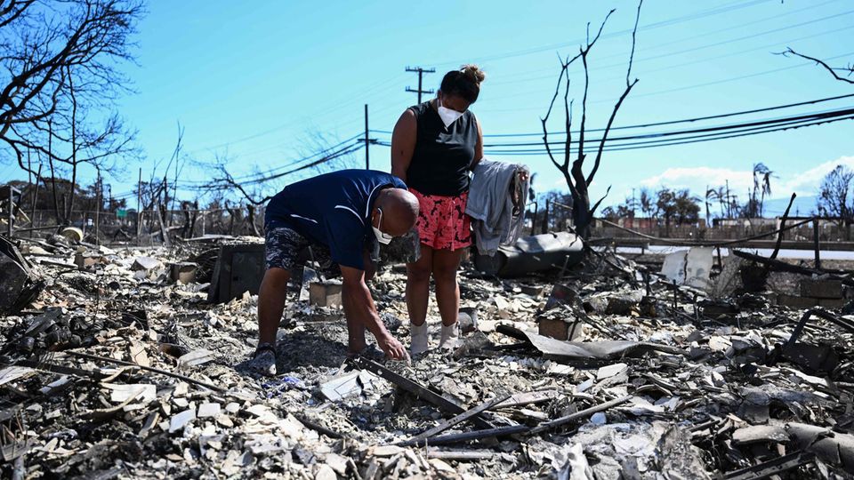 A family searches for items in their burned-down Lahaina home.
