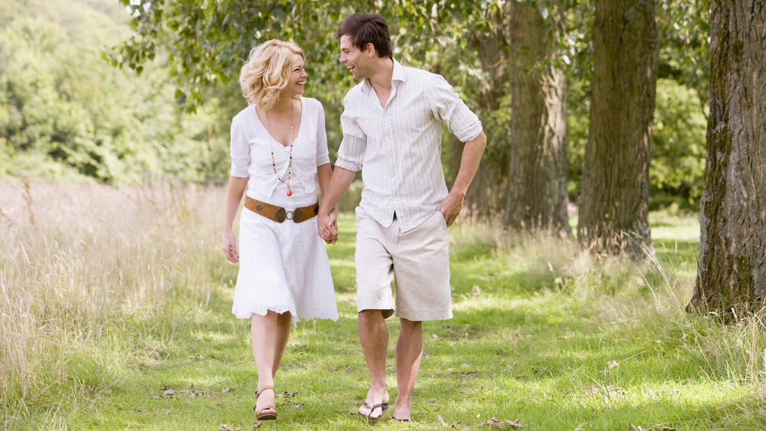Man and woman walk on a meadow path - towards the camera
