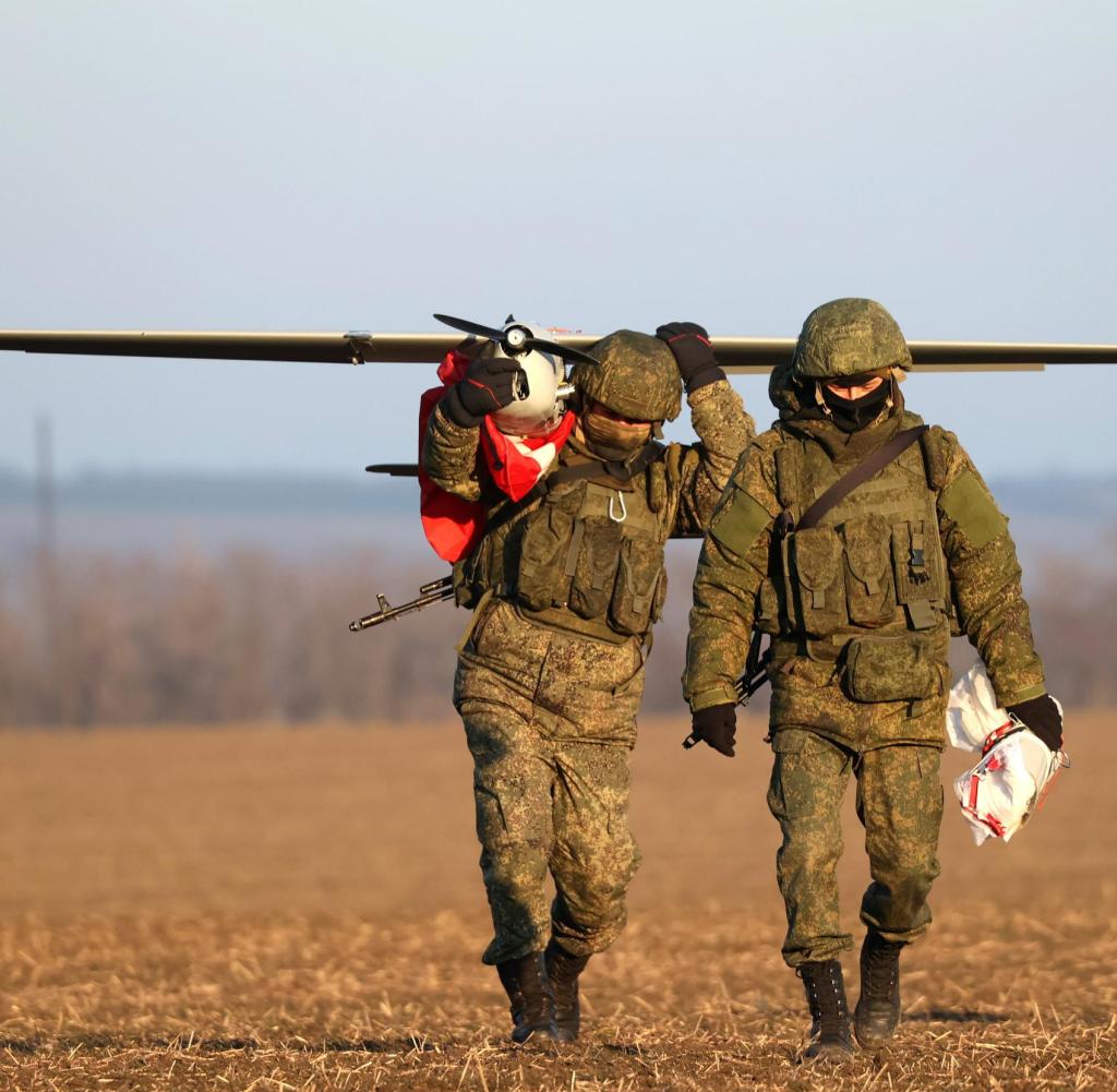 DIESES FOTO WIRD VON DER RUSSISCHEN STAATSAGENTUR TASS ZUR VERFÜGUNG GESTELLT. [RUSSIA, ZAPOROZHYE REGION - FEBRUARY 8, 2023: Servicemen carry an Orlan-10 unmanned aerial vehicle in the zone of Russia's special military operation. Russian servicemen use the UAV to locate enemy targets and adjust fire. The crew of an Akatsiya self-propelled gun destroys the targets. Sergei Malgavko/TASS]