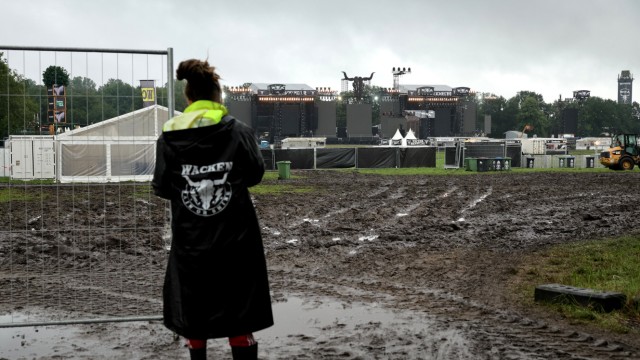 Heavy-Metal-Festival: Ein Metalfan steht vor einem noch geschlossenen Einlass zu den beiden Hauptbühnen auf dem schlammigen Festivalgelände.