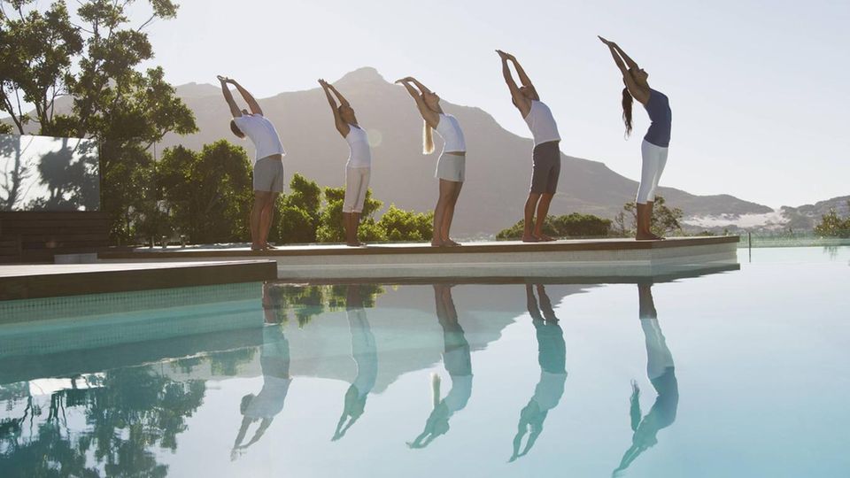 A group practices yoga by the pool