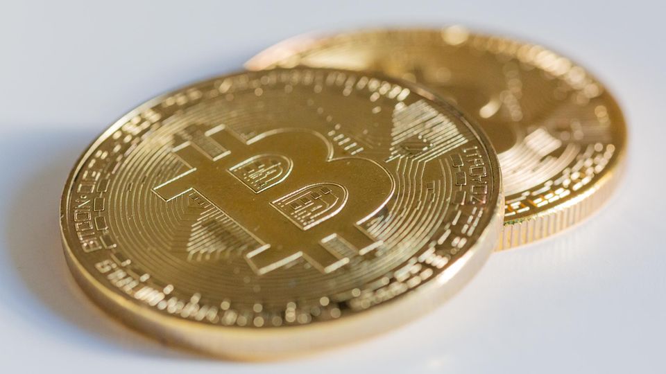 Two Bitcoin coins lie on a white table