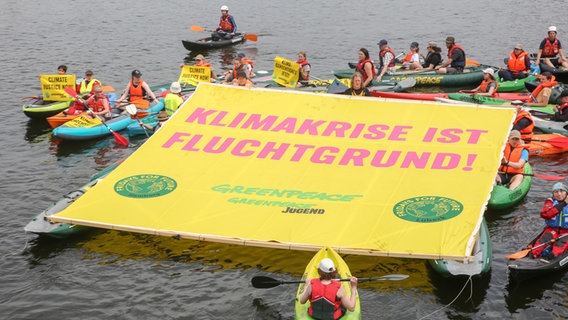 Members of Greenpeace and Fridays for Future with kayaks, inflatable boats and a large banner saying "Climate crisis is a reason for refugees!" on the Binnenalster in Hamburg.  © picture alliance / dpa Photo: Bodo Marks