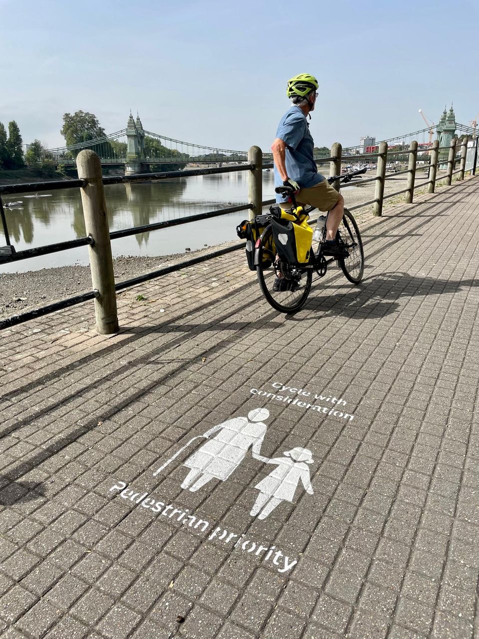 "Cycle considerately - pedestrians have priority here" stands on the Thames Path, which is shared by pedestrians and cyclists in Hammersmith