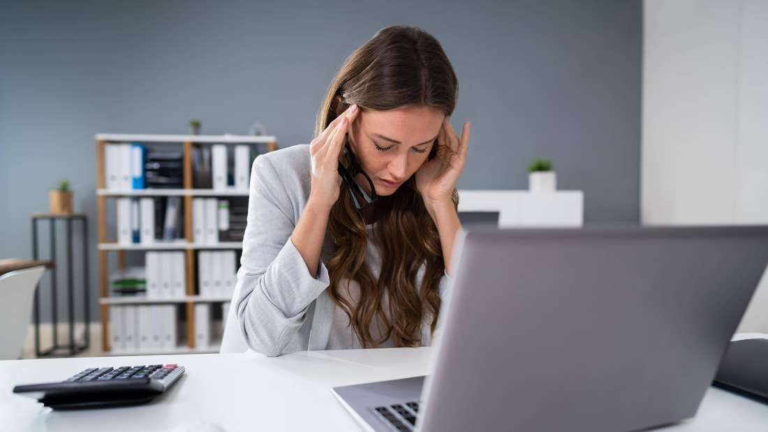 Woman at the computer under stress with a headache