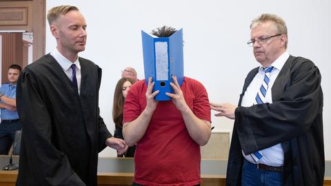 The defendant (M) is led into the hearing room in the Gießen regional court for the verdict to be announced. 