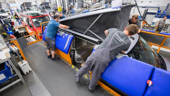 VW employees assemble the roof of a Volkswagen California motorhome.  © picture alliance/dpa Photo: Julian Stratenschulte