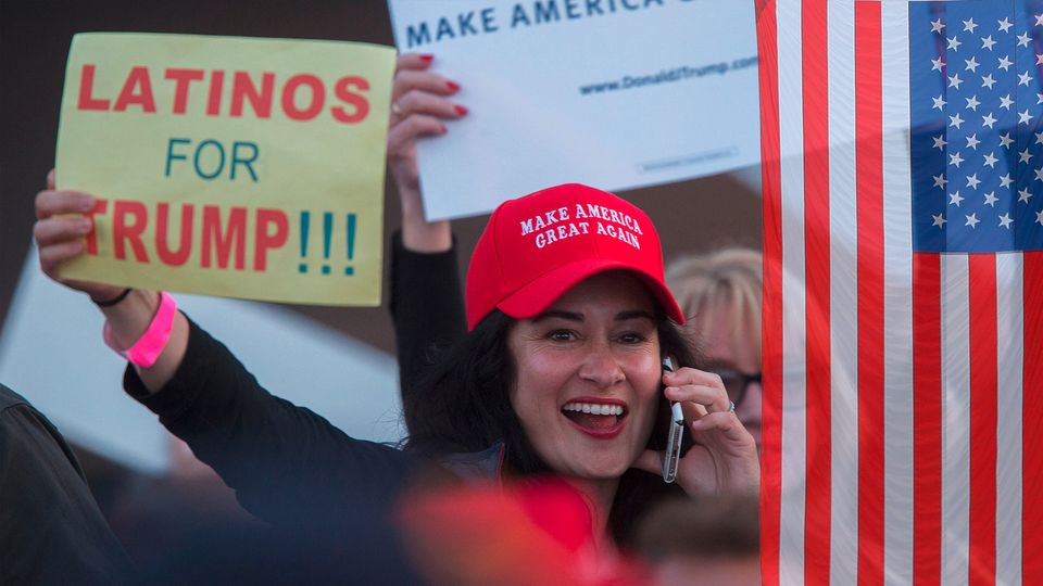 A woman wears a cap that says "Make America Great Again".  She holds a sign that says: "Latinos for Trump"