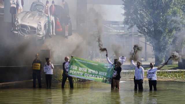 Protests against the IAA: Extinction Rebellion activists climb into the exhibition lake.  They are stained with black paint and burn smoke flares.