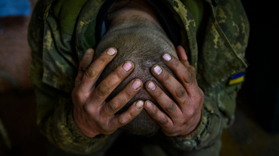 A Ukrainian soldier in Bakhmut clasps his hands above his head