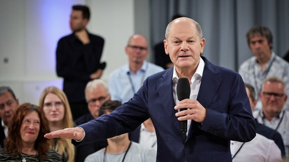 Chancellor Olaf Scholz speaks into a microphone during a discussion in Hamburg.  © picture alliance / dpa Photo: Christian Charisius