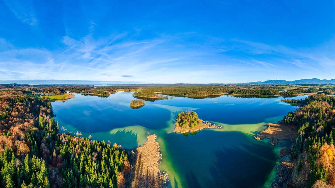 Dieses Bild zeigt den Großen Ostersee im Fünfseenland. Eindrucksvoll zu sehen sind das paradiesische Wasser mit seiner prächtigen Farbe und die vielfältige Umgebung rund um den See. Nicht umsonst ist Bayern auch für seine teils atemberaubende Seenlandschaft bekannt.