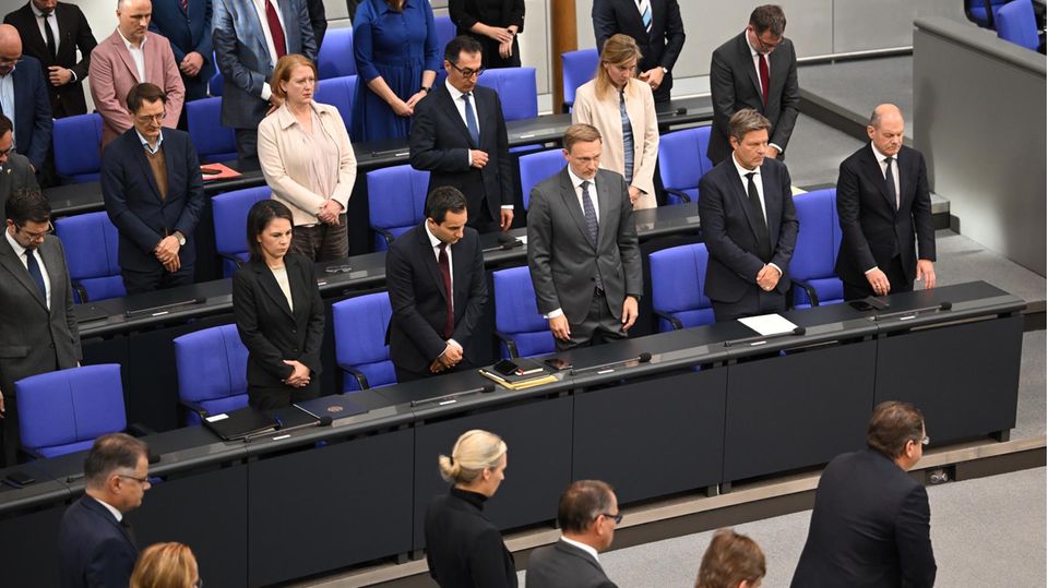 The traffic light cabinet members on the government bench take part in the minute's silence for the victims of the major Hamas attack