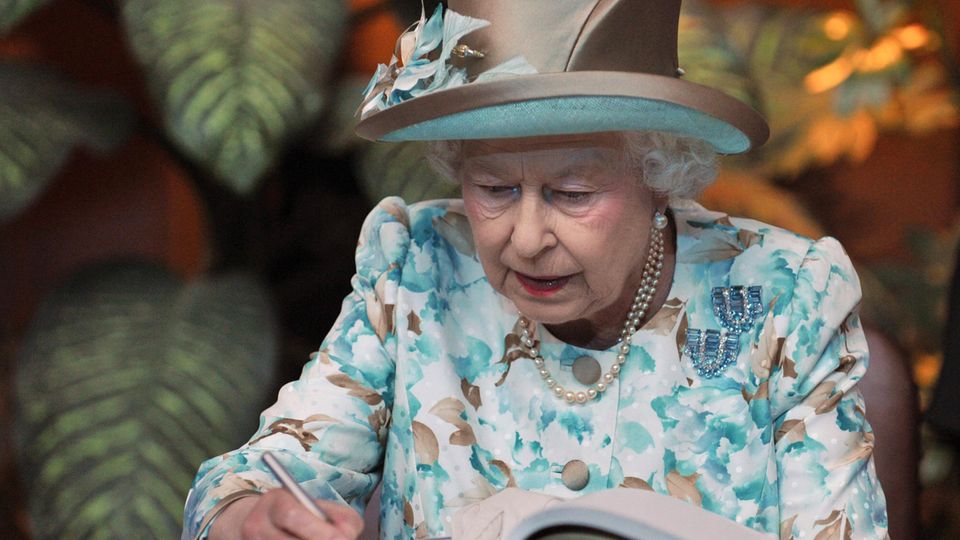 Queen Elizabeth II writes in a guest book